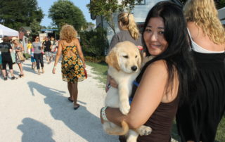young woman holding her golden retriever puppy at the cape may mac Craft beer, Music & Crab Festival
