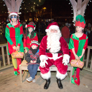 A child sitting with santa and his elves