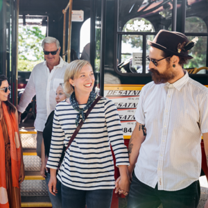 a young couple hold hands exiting the red and white cape may mac trolley