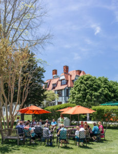 group of people sitting on the lawn of the emlen physick estate
