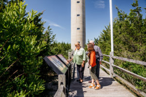 three people looking at information outside of the world war ii lookout tower museum