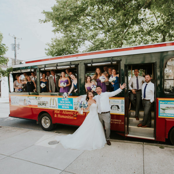 Wedding party posing in front of a red trolley