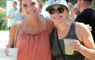 Two women smiling while holding drinks outside