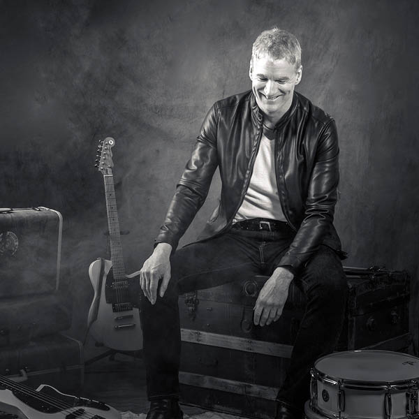 Elliott Lewis 600 black and white photo of man with guitar and drum