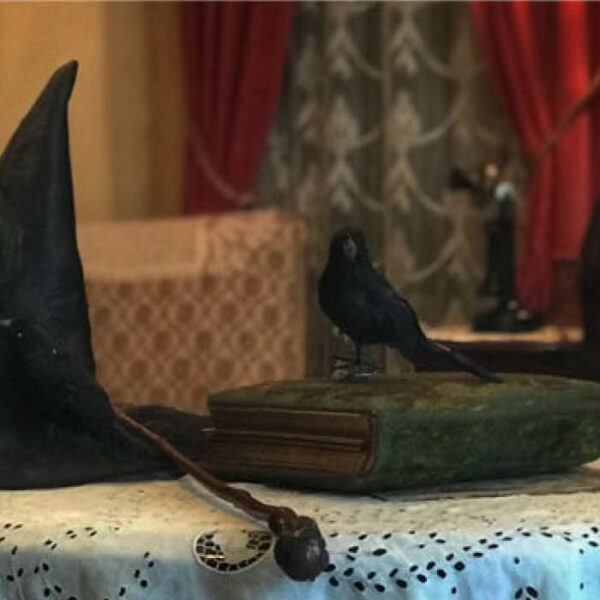 black witch hat with wand on an end table with crows