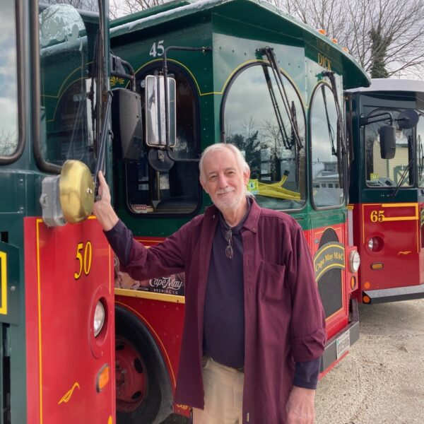 VOMFebruary23RogerHenry man standing next to a red and green trolley