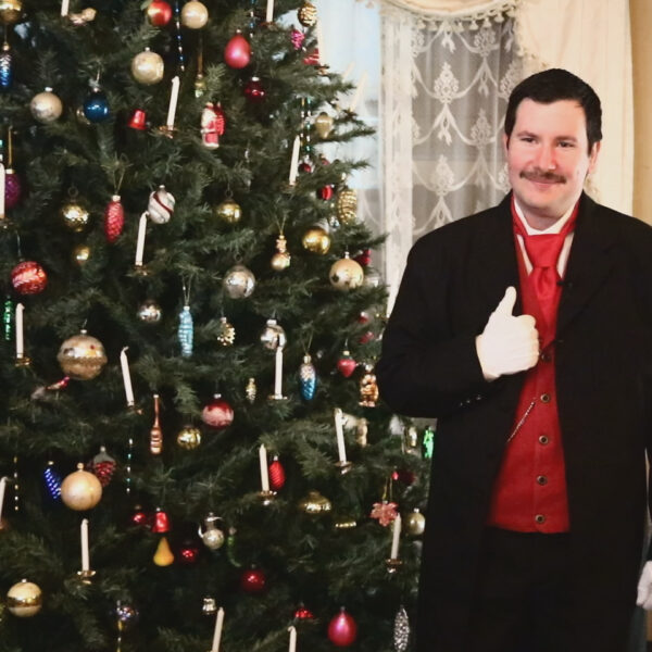 Dr. Physick Christmas 2020-12-11(1) (1) a photo of a man dressed in Victorian dress next to a Christmas tree