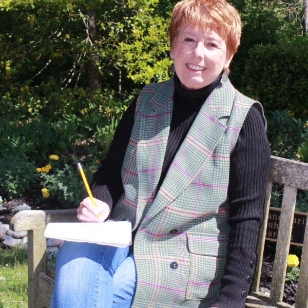 Sylvia Baer Poetry Workshop 23 (2) photo of a woman sitting outside on a bench with short red hair and a notepad and pencil