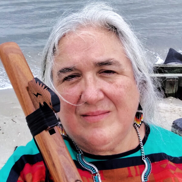 woman with grey hair standing on in front of the ocean