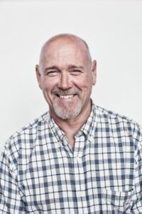 a white man smiling in a plaid shirt