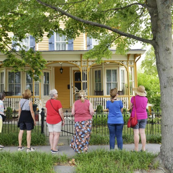people on a walking tour looking at a Victorian house
