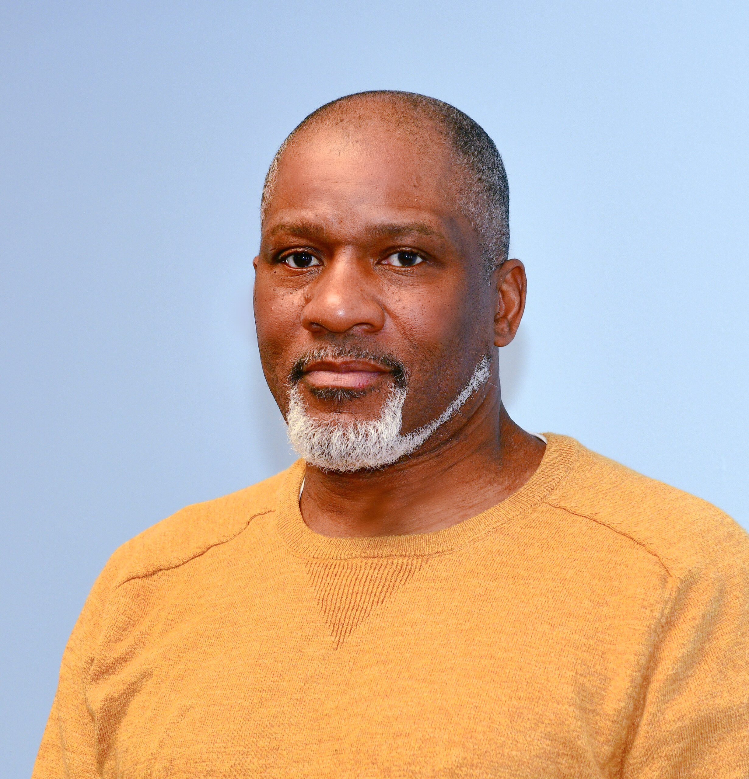 photo of a black man in front of a light blue backdrop